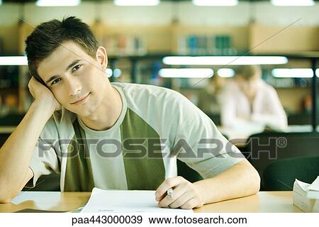 Male college student sitting in library, smiling at camera View Large Photo Image Stock Photo - Male college student sitting in library, smiling at camera. Fotosearch