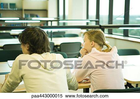 Stock Photography - Two college students sitting at table in library, rear view. Fotosearch