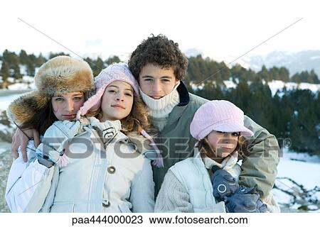 Stock Image - Four young siblings standing in snowy landscape, portrait. Fotosearch