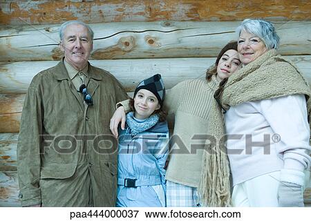 Stock Photo - Grandparents and granddaughters standing by chalet, portrait. Fotosearch