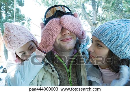 Teen girls with young man, one covering his eyes View Large Photo Image Stock Image - Teen girls with young man, one covering his eyes. Fotosearch