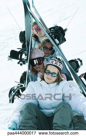 Young skiers sitting in snow with skis propped up over head, portrait View Large Photo Image Stock Photo - Young skiers sitting in snow with skis propped up over head, portrait. Fotosearch