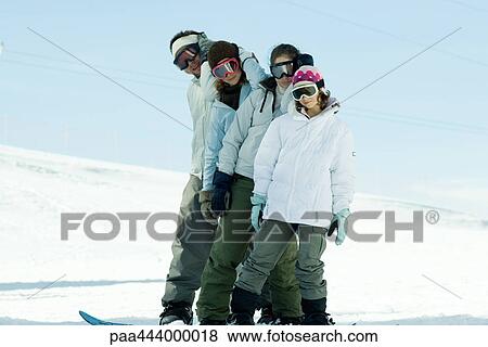 Stock Photo - Young snowboarders standing on ski slope, full length portrait . Fotosearch