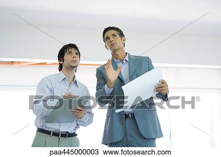 Stock Image - Architect and assistant inspecting home interior. Fotosearch