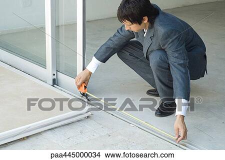 Man in suit measuring doorway View Large Photo Image Picture - Man in suit measuring doorway. Fotosearch