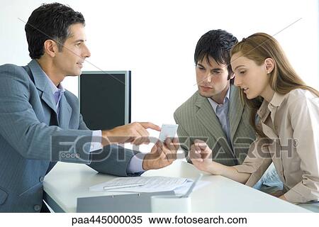 Man in suit sitting across from young couple, pointing to calculator View Large Photo Image Stock Photography - Man in suit sitting across from young couple, pointing to calculator. Fotosearch