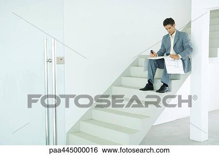 Man sitting on stairs, looking at blueprints View Large Photo Image Stock Photograph - Man sitting on stairs, looking at blueprints. Fotosearch