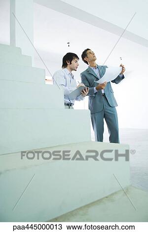 Stock Image - Two well-dressed men inspecting home interior. Fotosearch