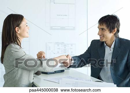 Woman and man shaking hands across table in architect firm View Large Photo Image Stock Photo - Woman and man shaking hands across table in architect firm. Fotosearch