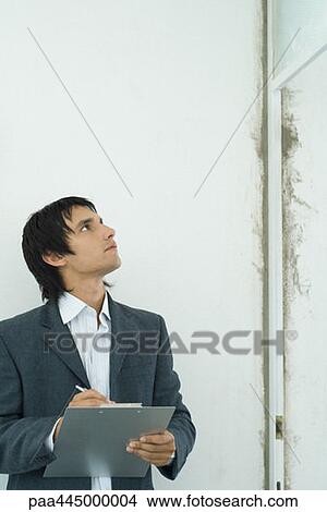 Picture - Young man inspecting home interior. Fotosearch