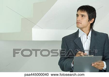 Stock Image - Young man with clipboard looking at home interior. Fotosearch