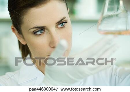 Young female researcher holding up flask, close-up View Large Photo Image Stock Photo - Young female researcher holding up flask, close-up. Fotosearch