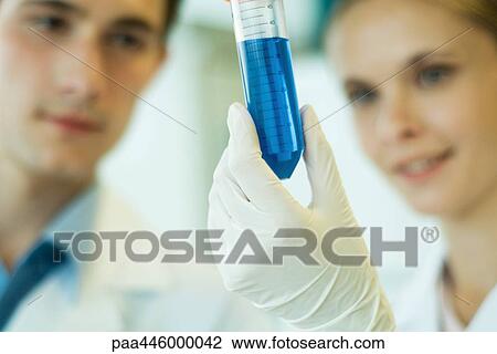 Stock Image - Young male and female lab workers, holding up test tube. Fotosearch
