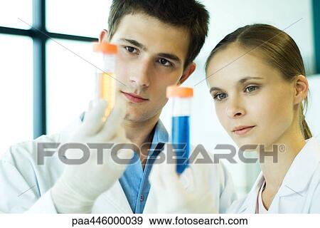Young male and female lab workers, holding up test tubes View Large Photo Image Stock Photo - Young male and female lab workers, holding up test tubes. Fotosearch