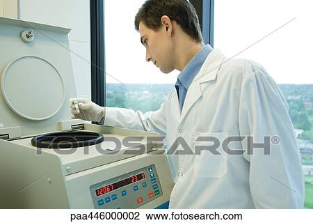 Stock Image - Young male scientist using centrifuge. Fotosearch