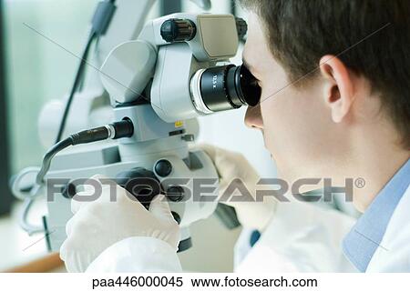 Stock Photography - Young male scientist using microscope. Fotosearch