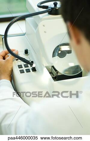 Stock Photography - Young male using science lab machine, over the shoulder view. Fotosearch