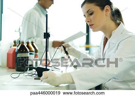 Stock Photo - Young woman working in scientific laboratory, taking notes. Fotosearch