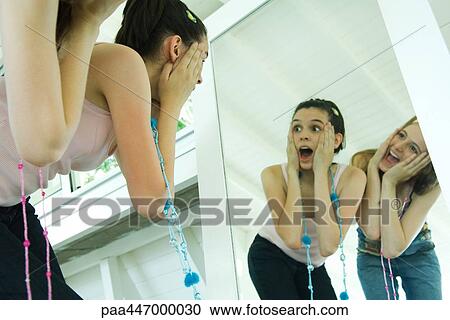 Two young friends bending over, looking at selves in mirror, hands on faces View Large Photo Image Stock Image - Two young friends bending over, looking at selves in mirror, hands on faces. Fotosearch
