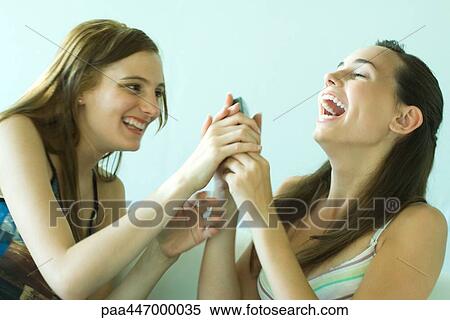 Two young friends laughing together, one taking phone from the other, blurred motion View Large Photo Image Stock Photography - Two young friends laughing together, one taking phone from the other, blurred motion. Fotosearch