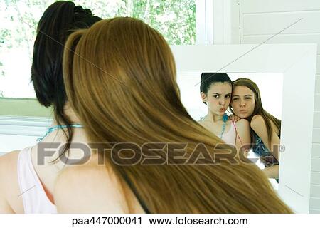 Two young friends looking at selves in mirror, puckering, rear view View Large Photo Image Stock Image - Two young friends looking at selves in mirror, puckering, rear view. Fotosearch