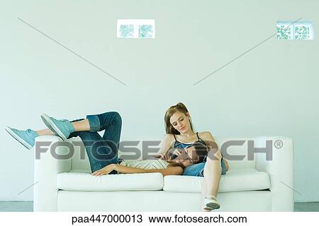 Two young friends on couch, one resting her head on the other's lap View Large Photo Image Stock Image - Two young friends on couch, one resting her head on the other's lap. Fotosearch