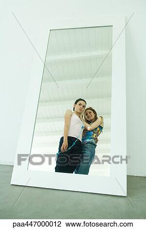 Two young friends standing together, looking at selves, reflected in mirror View Large Photo Image Stock Image - Two young friends standing together, looking at selves, reflected in mirror. Fotosearch