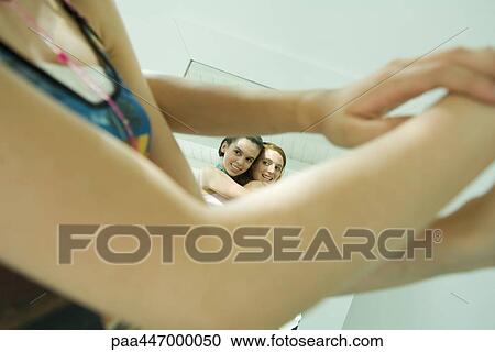 Two young girls looking at selves in mirror, smiling, cropped view through arms View Large Photo Image Stock Image - Two young girls looking at selves in mirror, smiling, cropped view through arms. Fotosearch