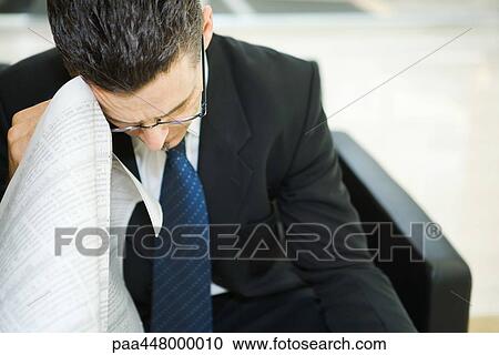 Businessman holding financial page of newspaper against lowered head View Large Photo Image Stock Image - Businessman holding financial page of newspaper against lowered head. Fotosearch