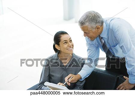 Businessman pointing at file held by female colleague View Large Photo Image Stock Photography - Businessman pointing at file held by female colleague. Fotosearch