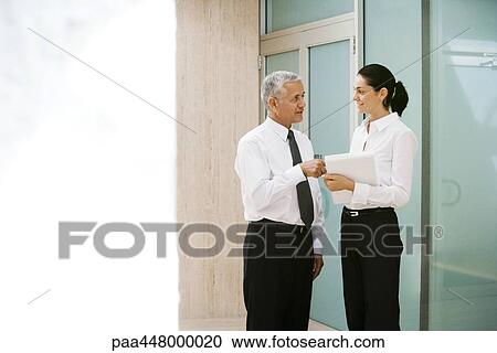 Mature businessman and young businesswoman discussing file View Large Photo Image Stock Image - Mature businessman and young businesswoman discussing file. Fotosearch