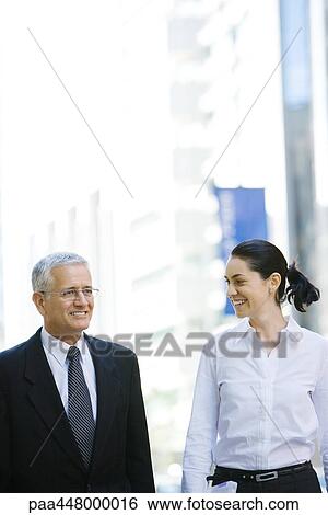 Mature businessman and young businesswoman side by side on city sidewalk, woman looking at man View Large Photo Image Stock Photograph - Mature businessman and young businesswoman side by side on city sidewalk, woman looking at man. Fotosearch