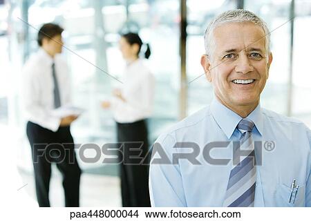 Mature businessman, colleagues talking in background View Large Photo Image Picture - Mature businessman, colleagues talking in background. Fotosearch