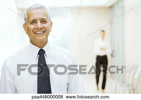 Mature businessman standing in hallway, smiling at camera, portrait View Large Photo Image Stock Photo - Mature businessman standing in hallway, smiling at camera, portrait. Fotosearch