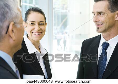 Stock Photo - Three business associates talking, smiling. Fotosearch