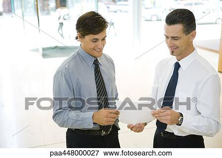 Two businessmen looking at document together View Large Photo Image Stock Photo - Two businessmen looking at document together. Fotosearch