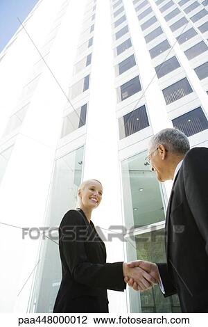 Young businesswoman shaking hands with mature businessman, low angle view View Large Photo Image Stock Image - Young businesswoman shaking hands with mature businessman, low angle view. Fotosearch