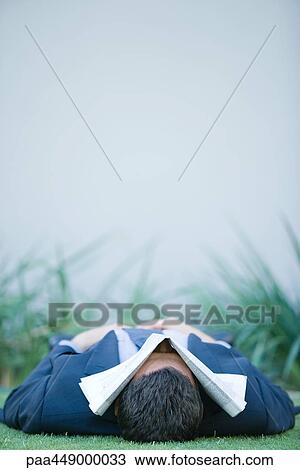 Businessman lying on grass, newspaper over face View Large Photo Image Stock Image - Businessman lying on grass, newspaper over face. Fotosearch