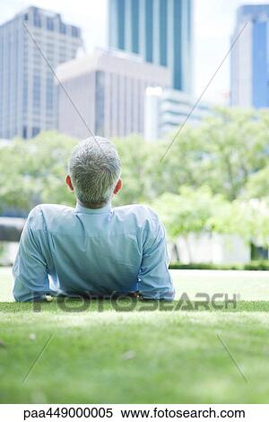 Businessman lying on grass, rear view View Large Photo Image Stock Photography - Businessman lying on grass, rear view. Fotosearch