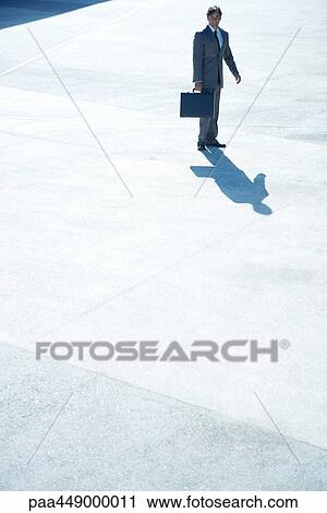 Stock Image - Businessman standing in esplanade holding briefcase. Fotosearch