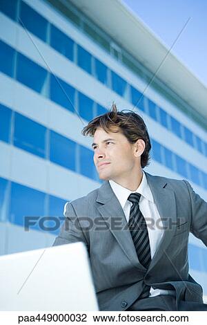 Stock Image - Businessman using laptop outdoors. Fotosearch