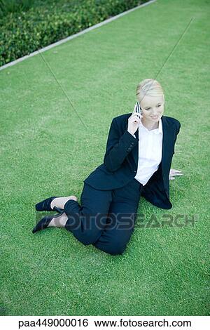 Businesswoman sitting on grass, using cell phone, high angle view View Large Photo Image Stock Photograph - Businesswoman sitting on grass, using cell phone, high angle view. Fotosearch