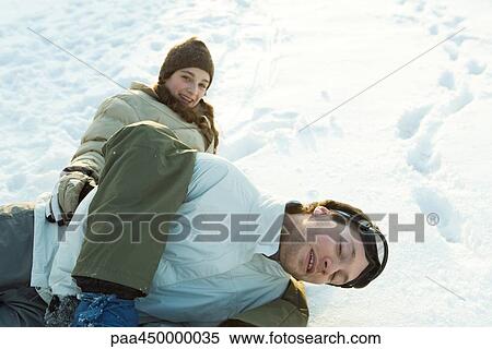 Stock Photography - Brother and sister play-fighting in snow, lying in the ground, smiling at camera. Fotosearch