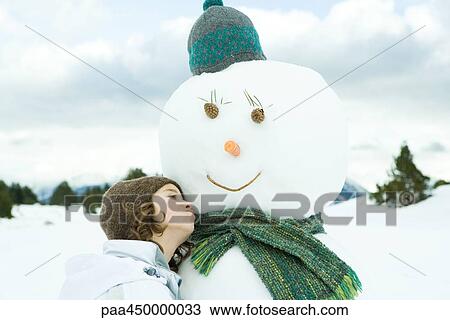 Girl leaning against snowman, looking away, portrait View Large Photo Image Stock Image - Girl leaning against snowman, looking away, portrait. Fotosearch