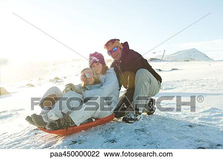 Mature man crouching behind sled with two daughters, smiling at camera View Large Photo Image Stock Image - Mature man crouching behind sled with two daughters, smiling at camera. Fotosearch