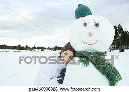 Teenage girl leaning against snowman, looking away, portrait View Large Photo Image Stock Photo - Teenage girl leaning against snowman, looking away, portrait. Fotosearch