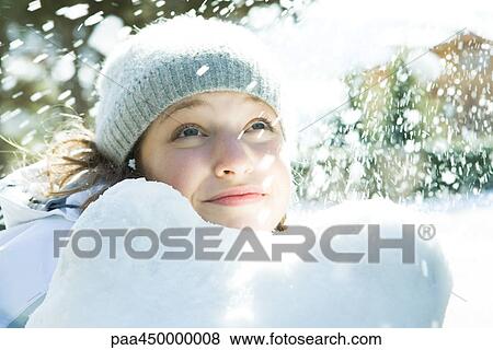Stock Photo - Teenage girl looking up at snow, smiling, portrait. Fotosearch