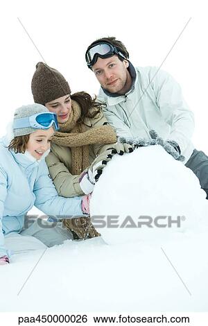 Three young friends making snowball, dressed in winter clothing, one looking at camera View Large Photo Image Stock Photograph - Three young friends making snowball, dressed in winter clothing, one looking at camera. Fotosearch