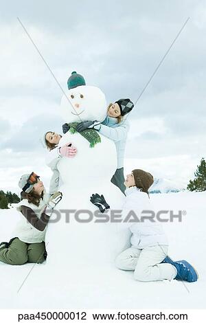 Young friends embracing snowman, smiling, full length View Large Photo Image Stock Image - Young friends embracing snowman, smiling, full length. Fotosearch