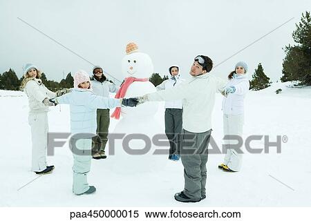 Young friends standing in circle around snowman, holding hands, smiling at camera View Large Photo Image Stock Photography - Young friends standing in circle around snowman, holding hands, smiling at camera. Fotosearch